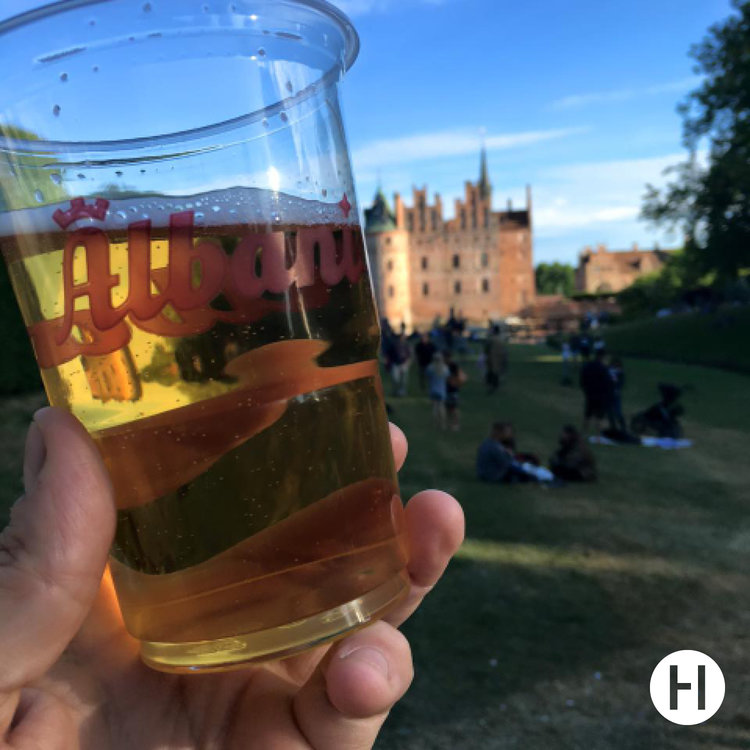 Man drikker Albani øl på Heartland Festival med Egeskov Slot i baggrunden