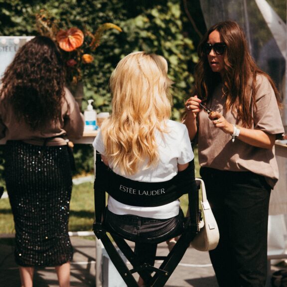 Blond langhåert pige som sidder i smikestol og får en make-over af en anden kvinde.