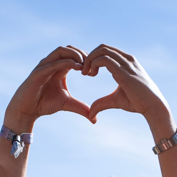 Hænder der former et hjerte på en blå himmel