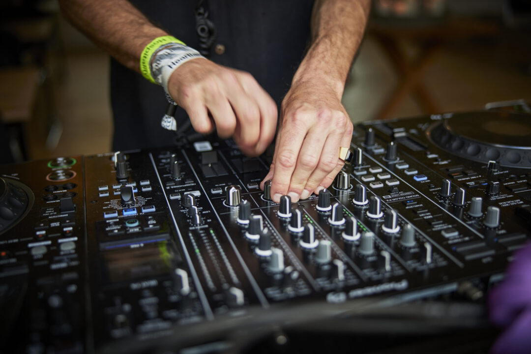Close-up af en DJ der står ved en DJ-pult og spiller musik