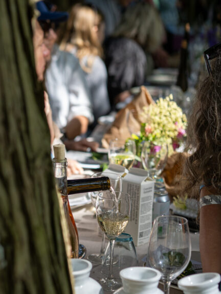 Hvidvin som bliver skænket i et vinglas på et flot dækket bord.