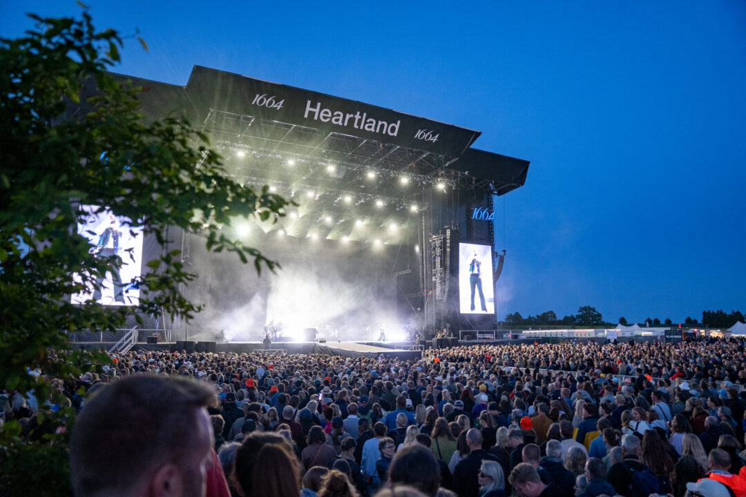 En stor folkemængde foran scene, hvor der bliver afholdt en koncert.
