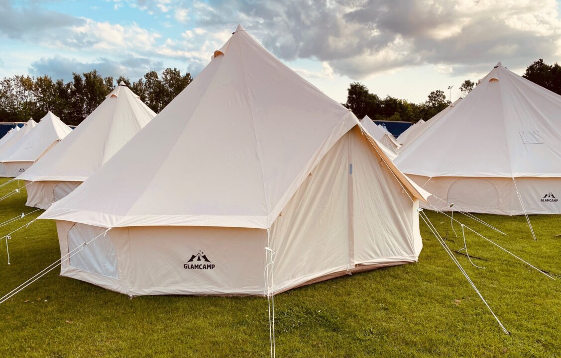 Smukt opslået campingtelt på grøn græsplæne med flot baggrund