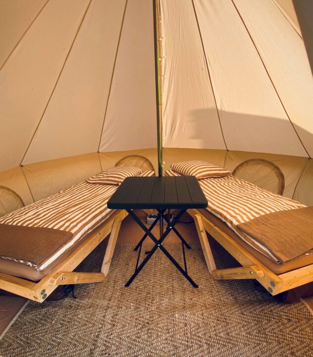 2 senge inde i et glamping telt med bord i midten
