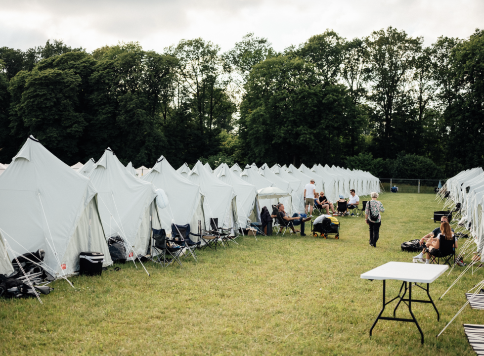 Tipi telte på række, hvor festivalsgæsterne sidder ude foran og hygger sig.