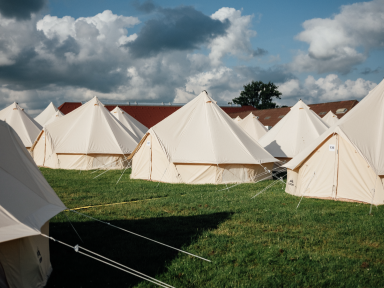 Hotel Heartlands glampingtelte på række. Græsset er grønt og himlen er blå.