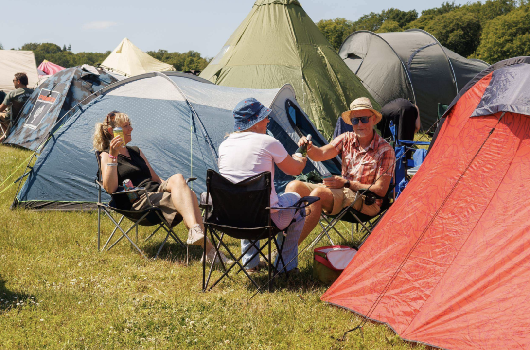 Festivalgæster skåler foran deres telt på campingrområdet