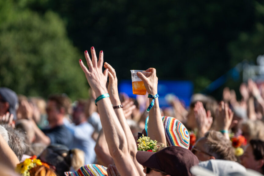 Hænder blandt publikum der holder en kop med en drink