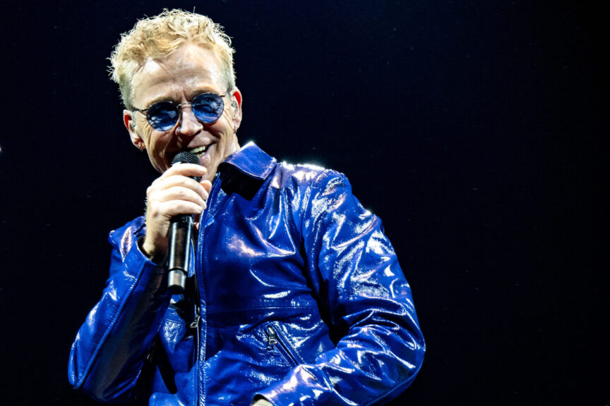 Thomas Helmig i blåt outfit og blå solbriller med en mikrofon i hånden